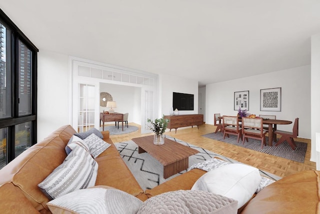 living room featuring light parquet floors, a wall of windows, and french doors