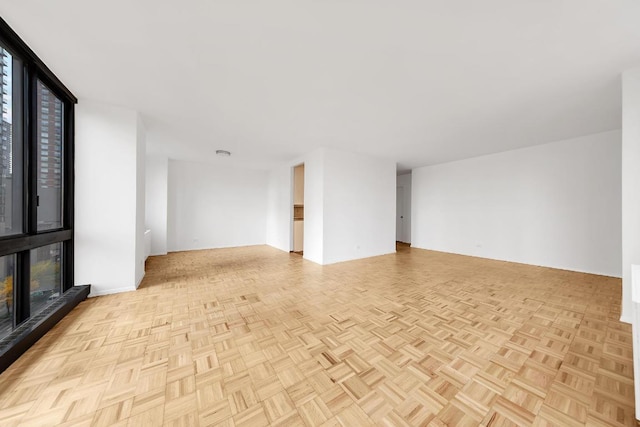 unfurnished living room featuring a wall of windows and light parquet flooring