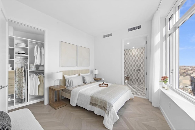 bedroom with connected bathroom, a closet, and light parquet flooring