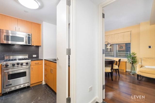 100 W 58th St Unit 11Ab, New York City, NY 10019 - kitchen featuring appliances with stainless steel finishes, dark countertops, decorative backsplash, and baseboards
