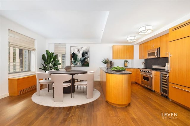 kitchen featuring dark countertops, beverage cooler, stainless steel appliances, and dark wood-style flooring