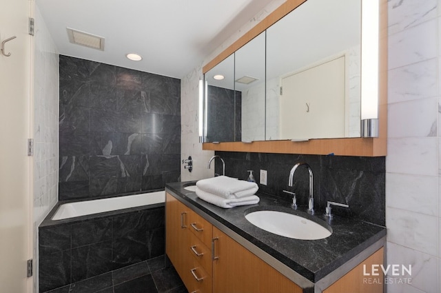 bathroom with vanity, tiled bath, and tile walls