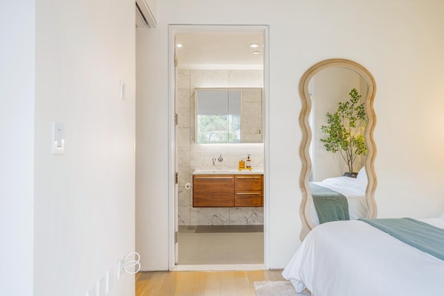 bedroom with ensuite bathroom and light wood finished floors