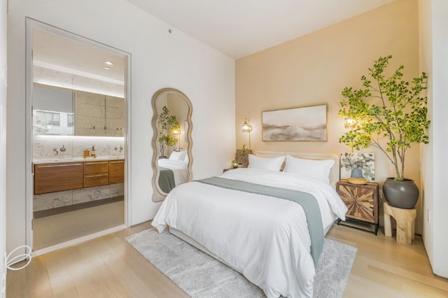 bedroom with light wood-style floors and ensuite bathroom