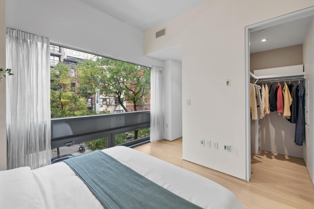 bedroom with light wood-style floors, a walk in closet, a closet, and visible vents