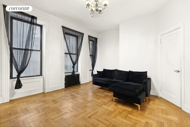 living area featuring light parquet floors, radiator heating unit, and a notable chandelier