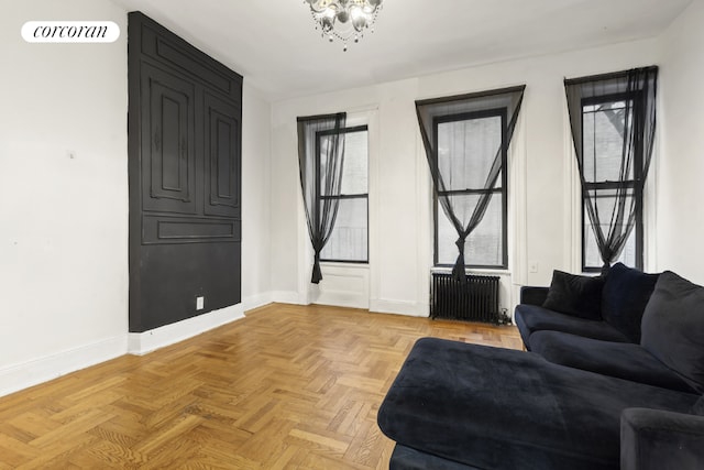 living area featuring radiator, a chandelier, and light parquet flooring