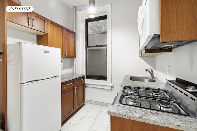 kitchen featuring white refrigerator, sink, light tile patterned flooring, light stone counters, and gas cooktop