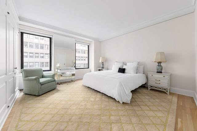 bedroom featuring light wood-style flooring, baseboards, and ornamental molding