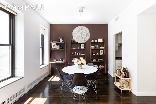 dining space featuring visible vents, baseboards, dark wood finished floors, and a baseboard heating unit