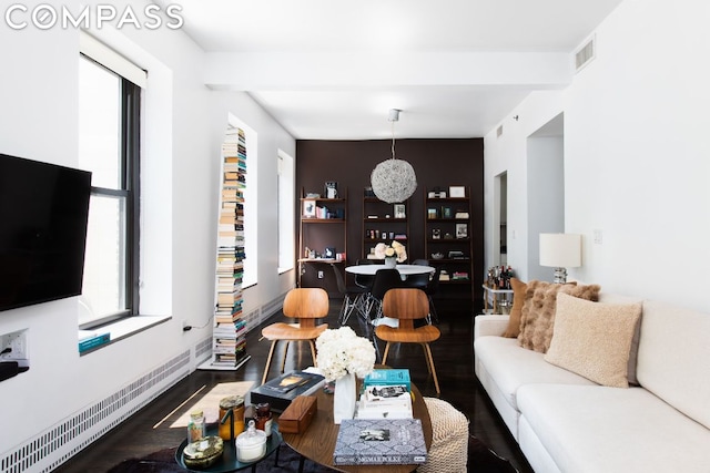 living room with beam ceiling, dark wood-type flooring, and a chandelier