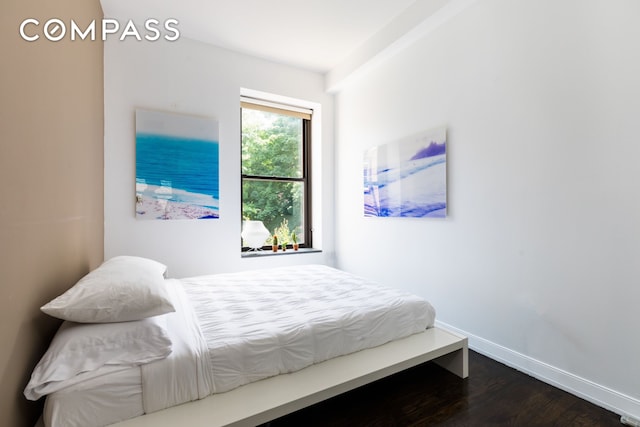 bedroom featuring baseboards and dark wood-type flooring