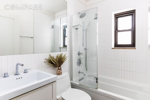 full bath featuring vanity, toilet, and combined bath / shower with glass door