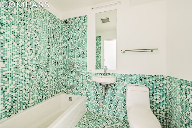 bathroom with sink, toilet, tile patterned floors, and tile walls