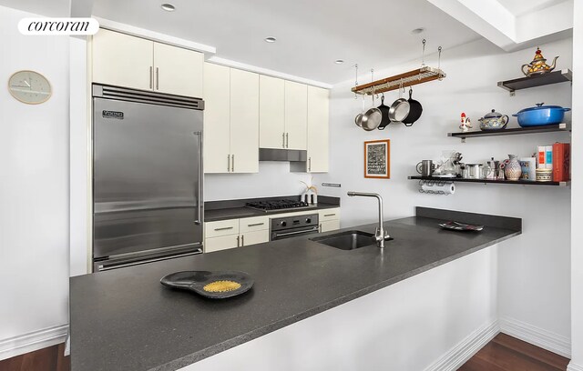 1 Hanson Pl Unit 9B, New York City, NY 11217 - kitchen with stainless steel appliances, a sink, dark countertops, under cabinet range hood, and baseboards