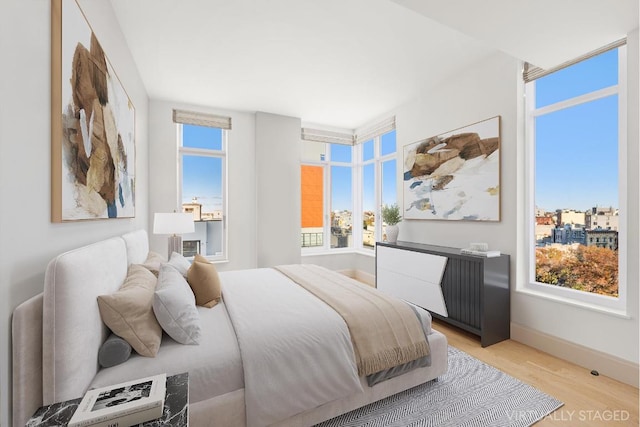 bedroom with light wood-style flooring, multiple windows, and baseboards