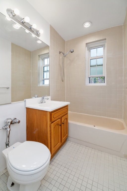 full bathroom featuring tiled shower / bath, plenty of natural light, toilet, and vanity