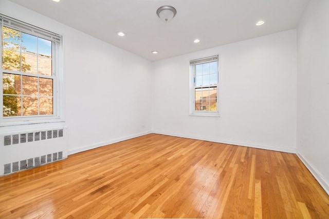 unfurnished room featuring radiator and light hardwood / wood-style floors