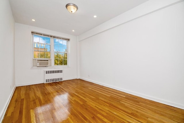 unfurnished room featuring cooling unit, radiator, and wood-type flooring