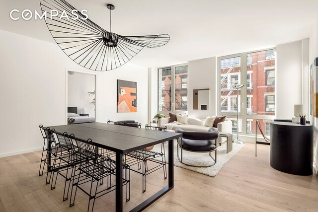 dining area featuring light wood-type flooring, baseboards, and a wall of windows