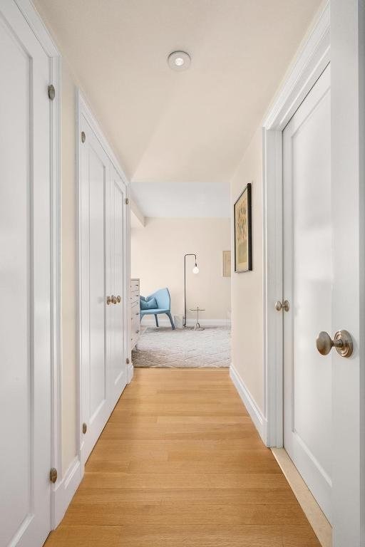 corridor with lofted ceiling and light wood-type flooring