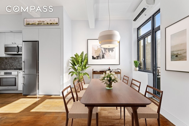 dining room featuring dark wood-style floors, an AC wall unit, baseboards, and beam ceiling