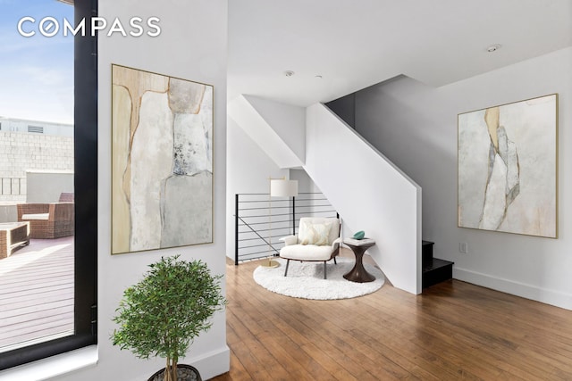 living area featuring baseboards, stairway, a fireplace with raised hearth, and wood finished floors