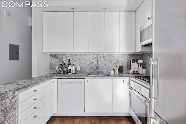 kitchen featuring white cabinets, dishwasher, sink, oven, and light stone counters