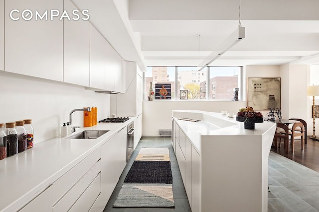 kitchen featuring stainless steel appliances, white cabinetry, sink, and pendant lighting