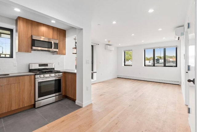 kitchen featuring appliances with stainless steel finishes, an AC wall unit, baseboard heating, and decorative backsplash