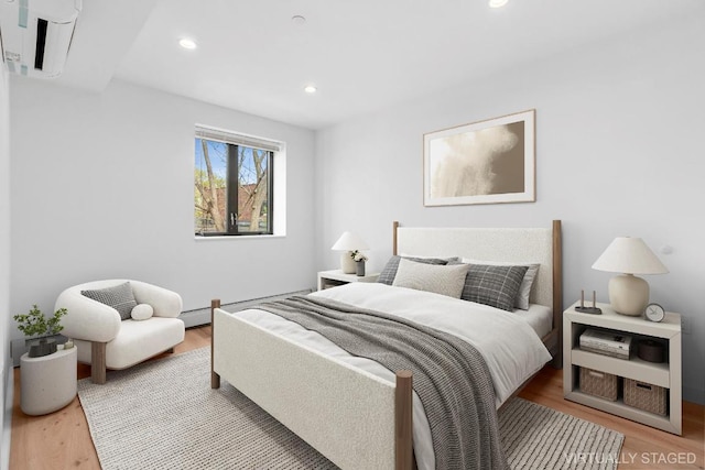 bedroom featuring baseboard heating and light hardwood / wood-style flooring