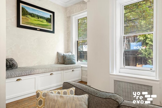 sitting room with radiator, crown molding, and wood finished floors