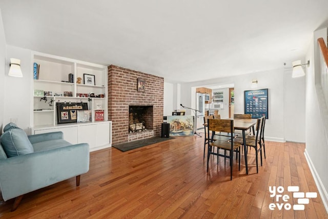 dining space with baseboards, a brick fireplace, light wood-style flooring, and built in features