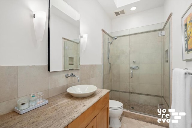 bathroom featuring a shower with door, tile patterned flooring, a skylight, vanity, and toilet