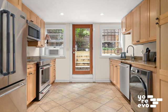 kitchen featuring light tile patterned floors, washer / clothes dryer, appliances with stainless steel finishes, light brown cabinets, and a sink