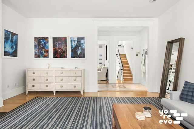 unfurnished living room with stairs, baseboards, and wood finished floors