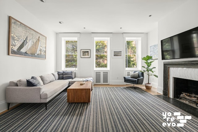 living room featuring a fireplace, wood finished floors, visible vents, and baseboards