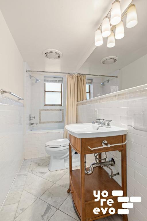 bathroom featuring toilet, tiled shower / bath combo, visible vents, and tile walls