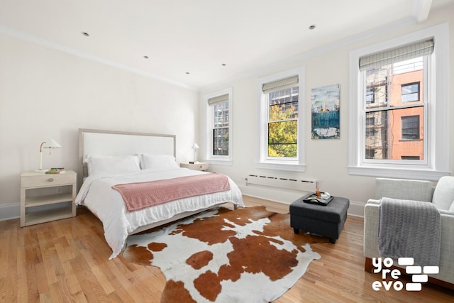 bedroom with light wood finished floors, a baseboard radiator, and crown molding