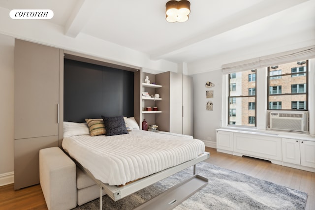 40 W 72nd St Unit 111, New York City, NY 10023 - bedroom with beamed ceiling, wood finished floors, cooling unit, and baseboards