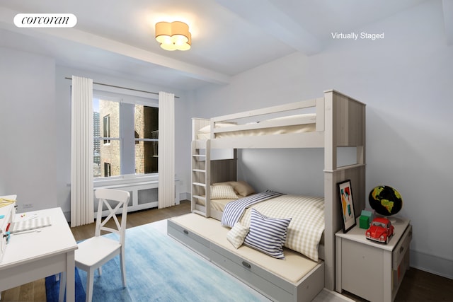 bedroom featuring beam ceiling, wood finished floors, and radiator heating unit