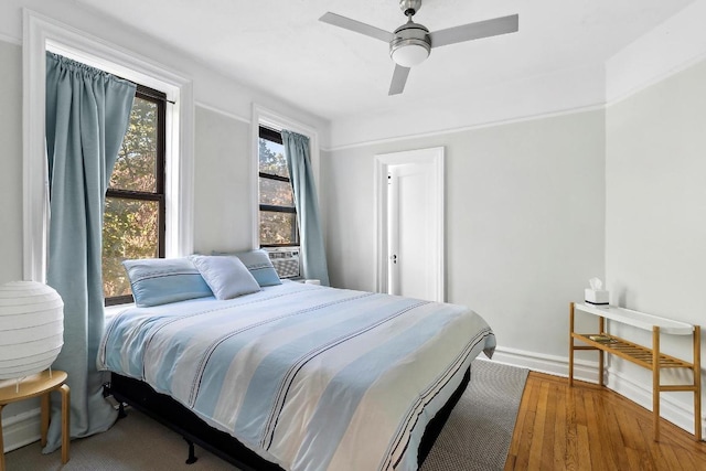 bedroom with cooling unit, wood-type flooring, and ceiling fan