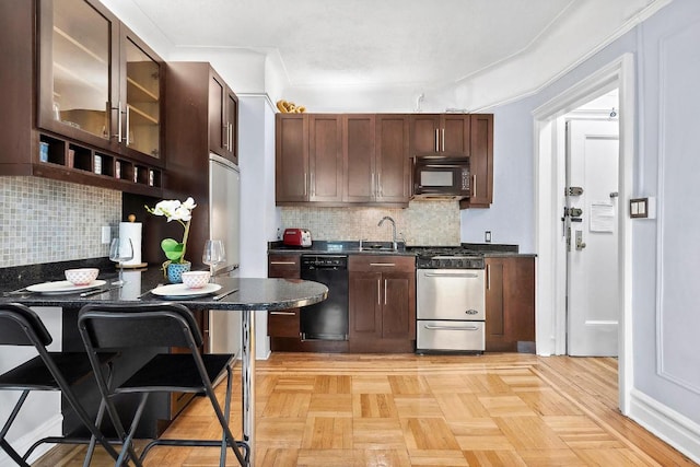 kitchen featuring tasteful backsplash, light parquet flooring, a kitchen breakfast bar, and black appliances