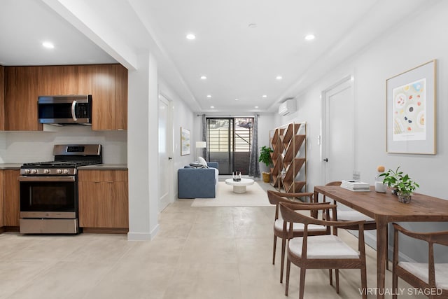 kitchen with appliances with stainless steel finishes, brown cabinets, backsplash, and a wall mounted air conditioner