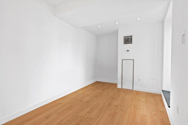 office with radiator heating unit and light hardwood / wood-style flooring