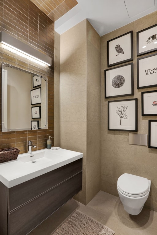 bathroom featuring tile walls, vanity, toilet, and backsplash