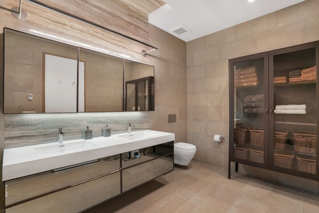 bathroom featuring toilet, tile walls, and vanity