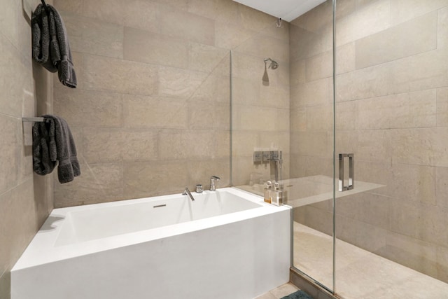 bathroom featuring tile walls and shower with separate bathtub