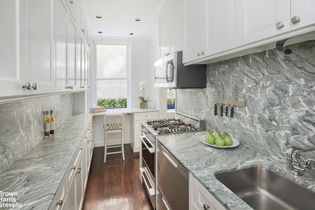 kitchen featuring appliances with stainless steel finishes, white cabinetry, tasteful backsplash, sink, and light stone counters