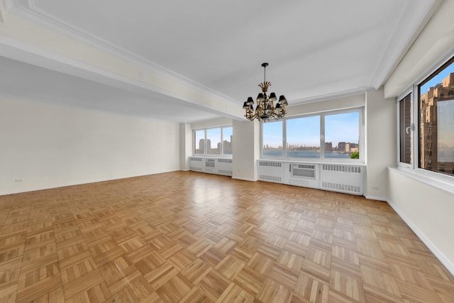 spare room featuring radiator, baseboards, a chandelier, and crown molding